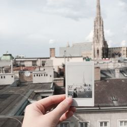 Close-up of man photographing cityscape against sky