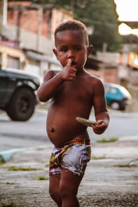 Portrait of shirtless boy standing on street