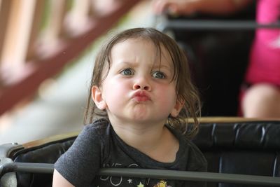 Cute girl puckering while sitting on seat