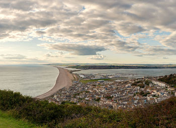 Aerial view of townscape by sea against sky