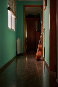 A guitar is leaning against the wall of a hallway in a house