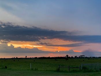 Scenic view of farm against sky during sunset