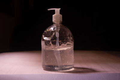 Close-up of glass bottle on table against black background