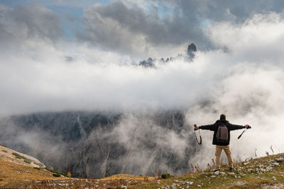 Rear view of man standing on mountain against sky