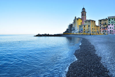 View of sea and buildings against clear blue sky