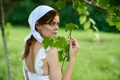 Side view of young woman standing amidst plants