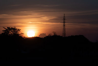 Silhouette electricity pylon against sky during sunset