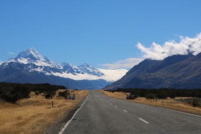 Road by mountains against blue sky