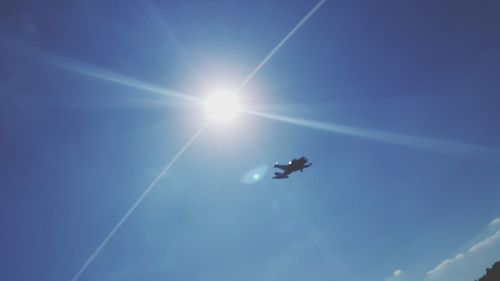 Low angle view of airplane flying against blue sky