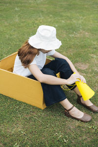 Full length of woman sitting with megaphone in box on grass