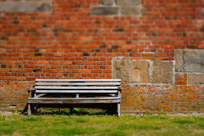 Empty bench against brick wall