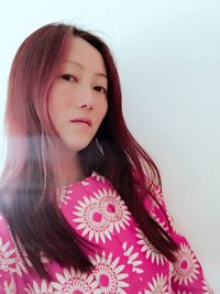 Portrait of beautiful young woman standing against white background