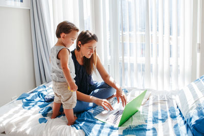 Mother working on laptop while boy looking at it