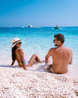 Rear view of woman sitting at beach