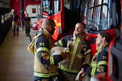 Firefighters in uniform talking while standing at fire station