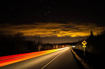 Light trails on road against sky at night