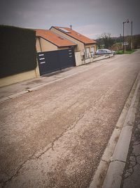 Road by building on field against sky