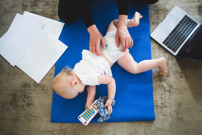 High angle view of working mother caring daughter on exercise mat at home