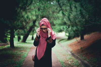 Woman in eyeglasses standing against in park