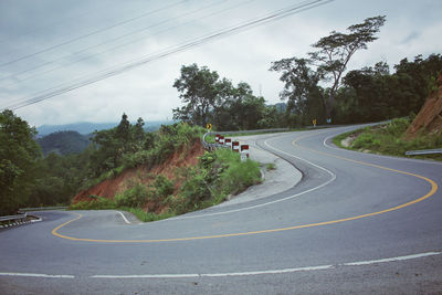 Road by trees against sky
