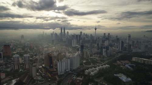 Aerial view of cityscape against cloudy sky at dusk