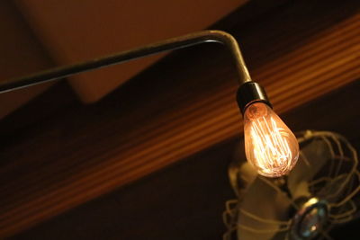 Low angle view of illuminated light bulb against ceiling