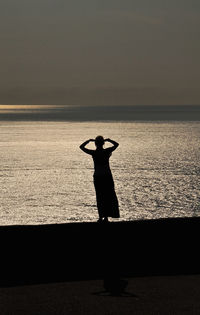 Silhouette man standing on beach against sky