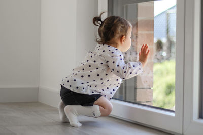 Little girl with ponytails looks out the window. new home rental.