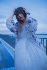 Portrait of young woman standing against sky