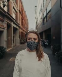 Portrait of young woman wearing mask standing outdoors