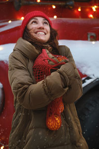 Happy woman near london double decker red old bus in winter with reusable bag of oranges. christmas