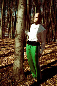 Woman standing by tree trunk in forest