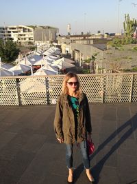 Woman standing against railing on sunny day