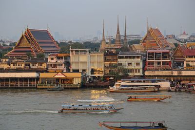 High angle view of boats sailing on river against buildings