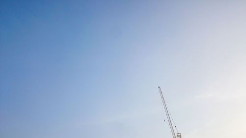 Low angle view of crane against clear blue sky