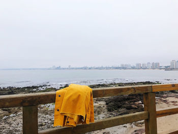 Jacket on railing at beach against clear sky