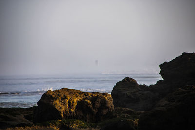 Rock formation on beach against sky