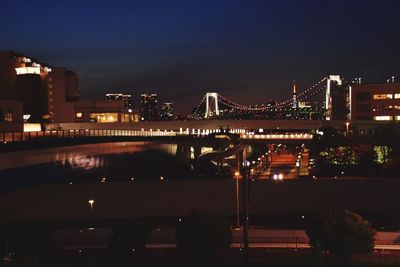 Illuminated bridge over river at night