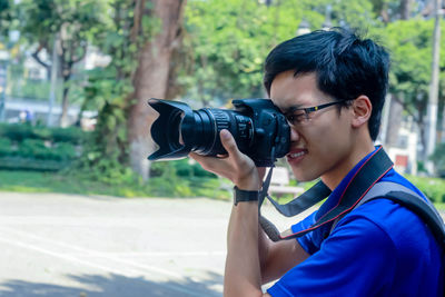 Vietnamese man taking a photo with dslr camera in the park