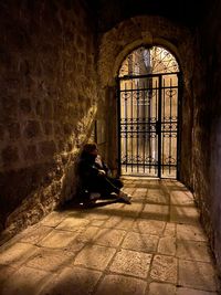 Side view of woman sitting in abandoned building