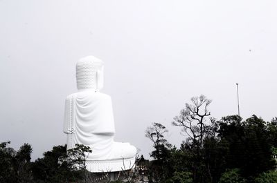Statue of buddha against trees and sky