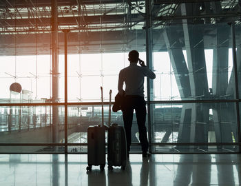 Rear view of man standing by window at airport