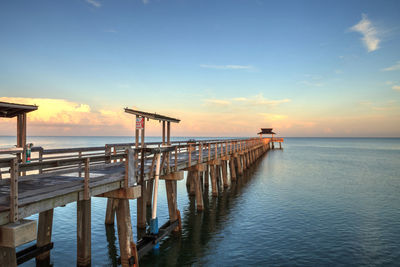 Pier over sea against sky during sunset