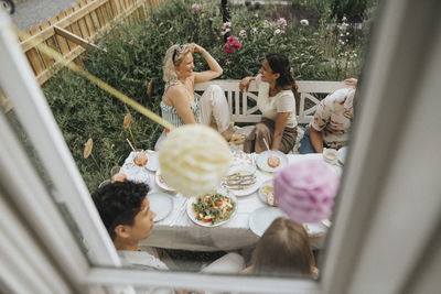 High angle view of happy friends celebrating dinner party seen through cafe window