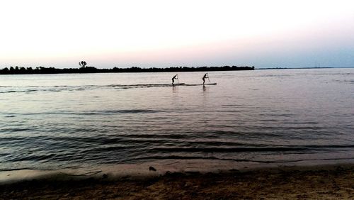 Silhouette people on beach against clear sky