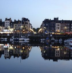 Reflection of illuminated buildings in lake against sky