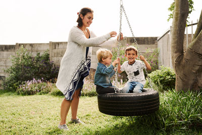 Mother playing with kids sitting on swing