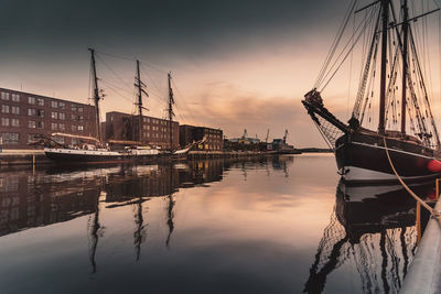 Sailboats moored in sea against sky during sunset