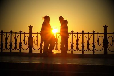 Silhouette people by sea against clear sky during sunset