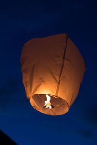 Low angle view of illuminated lantern against blue sky